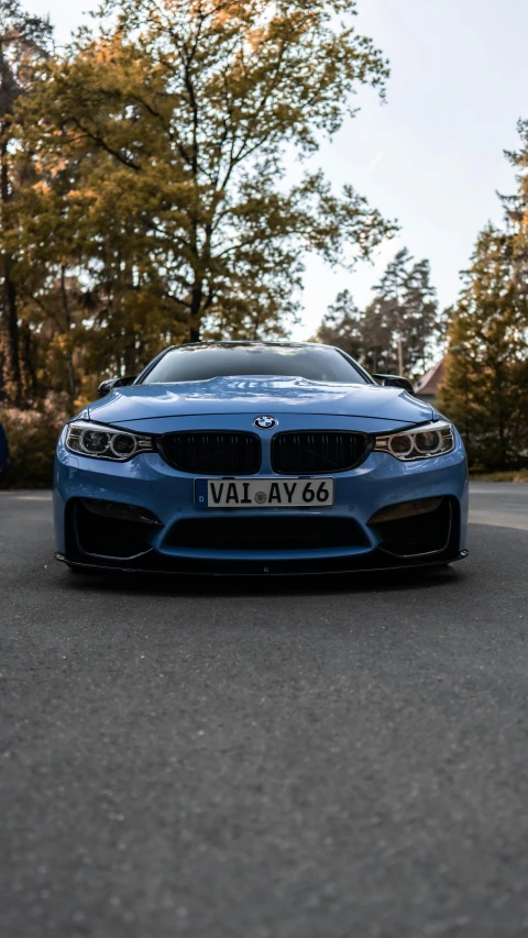 the front end of a blue car parked on a street