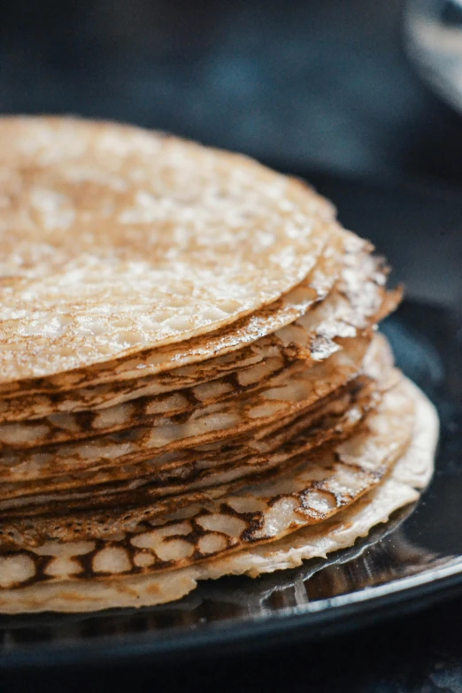 a stack of pancakes sitting on top of a black plate, an album cover, unsplash, baroque, russia, intricate wrinkles, 15081959 21121991 01012000 4k, low detail