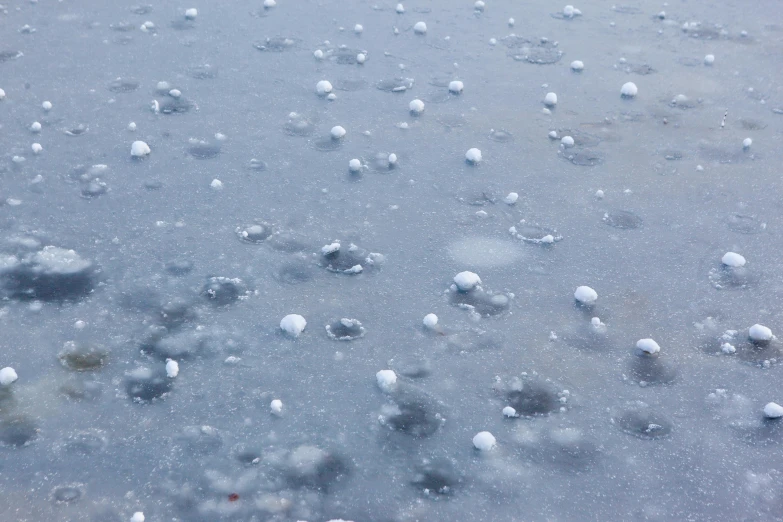 a bunch of bubbles floating on top of a body of water, inspired by Vija Celmins, trending on unsplash, land art, severe snow, low pressure system, many cryogenic pods, wet pavement