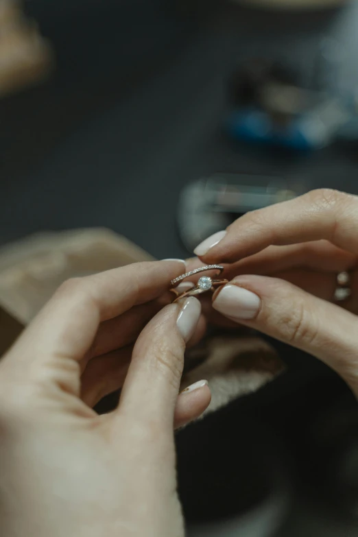 a close up of a person putting a ring on another person's finger, inspired by L. A. Ring, in a workshop, chaumet, teaser, crafting