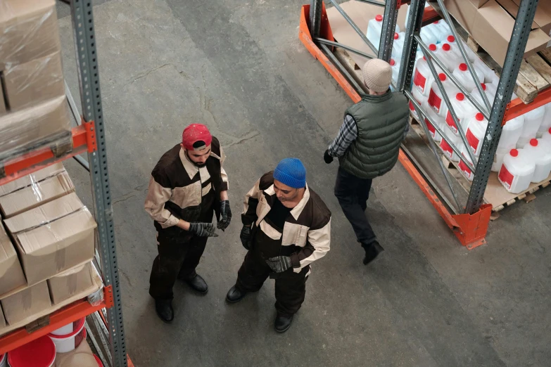 a group of men standing next to each other in a warehouse, inspired by Andreas Gursky, arbeitsrat für kunst, medium shot of two characters, costume, brown, a high angle shot