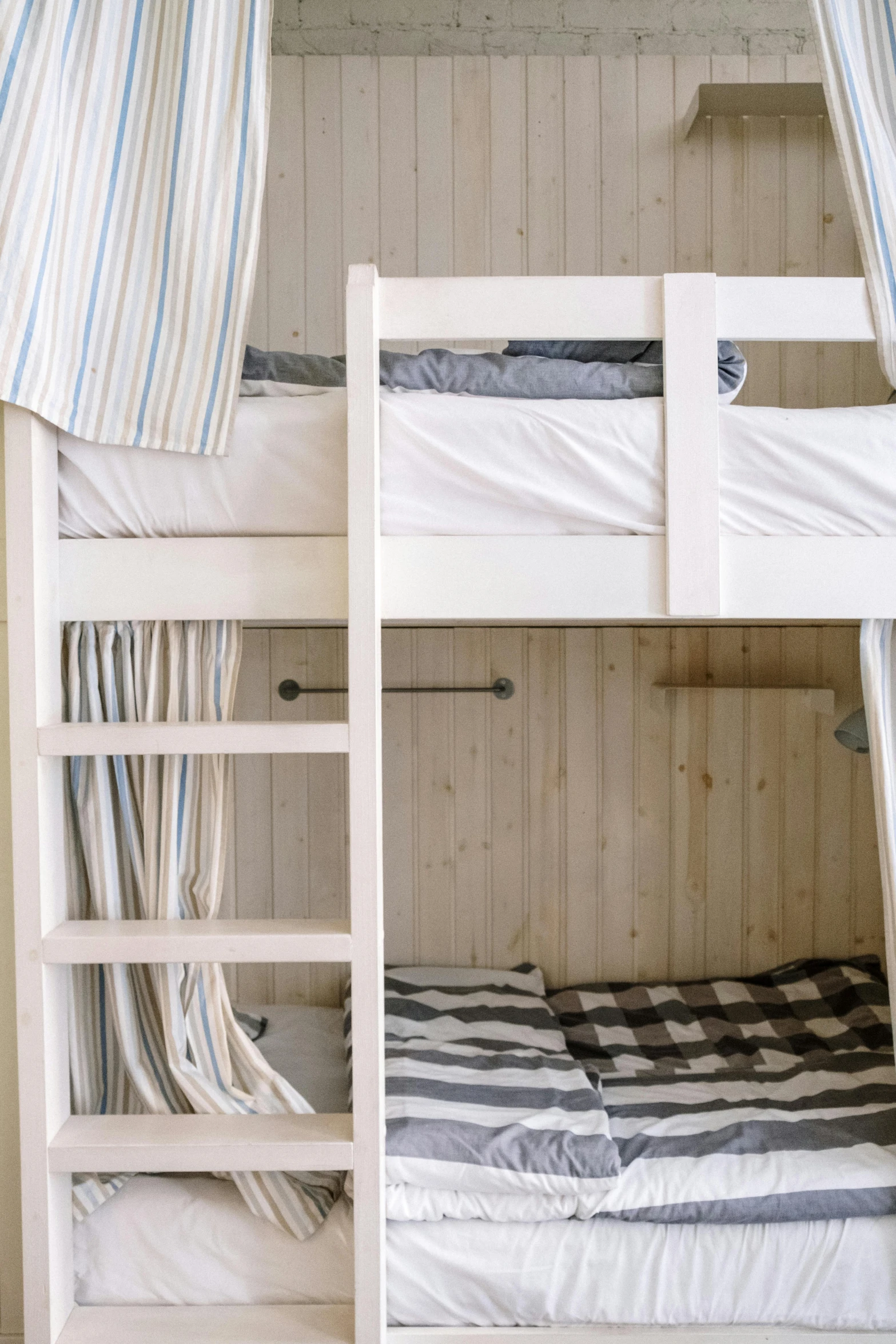 bunk beds in a white wood cabin with striped bedding