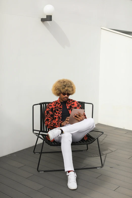 a person sitting on a chair in a room, inspired by Barkley Hendricks, trending on unsplash, afrofuturism, blond boy, al fresco, red suit, curls on top