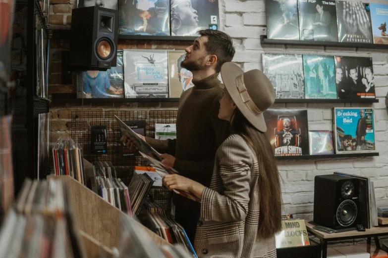 a man and woman looking at cds in a record store, an album cover, pexels contest winner, brown, australian, casually dressed, music poster