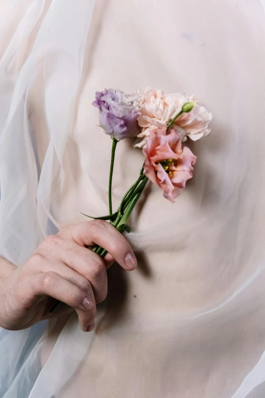 a person wearing a white dress and holding flowers