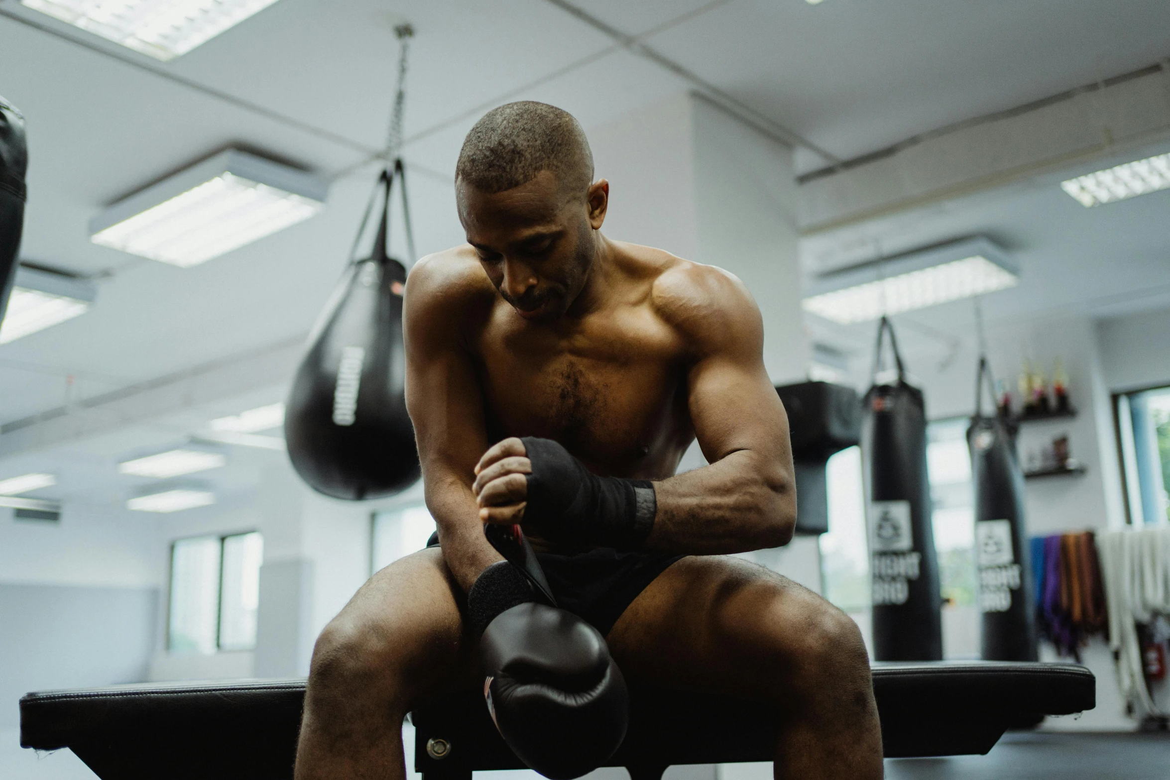 a man sitting on top of a bench next to a punching bag, profile image