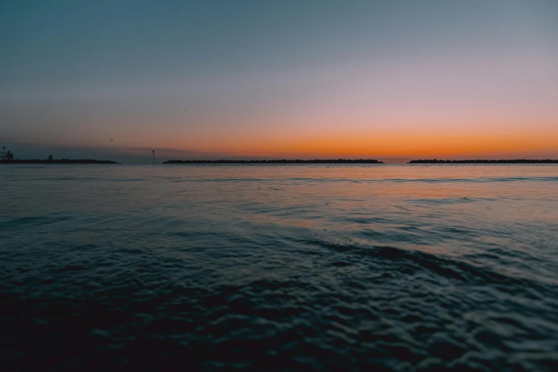 the sun is setting over a body of water, pexels contest winner, minimalism, ultrawide angle cinematic view, low quality footage, looking left, colored photo