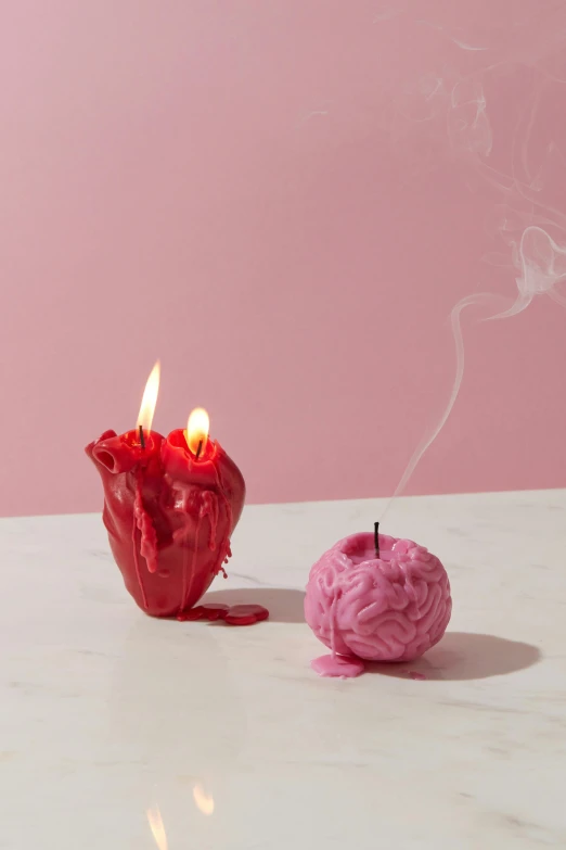 two candles sitting next to each other on a table, a surrealist sculpture, inspired by Marina Abramović, vanitas, featuring pink brains, red smoke, candy apple, neural