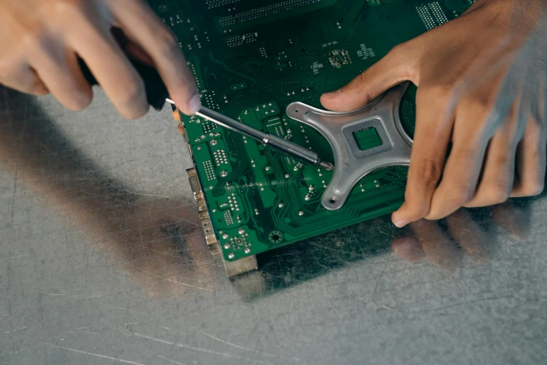 a close up of a person working on a circuit board, by Matthias Stom, unsplash, assemblage, promo image, repairing the other one, steel plating, a green