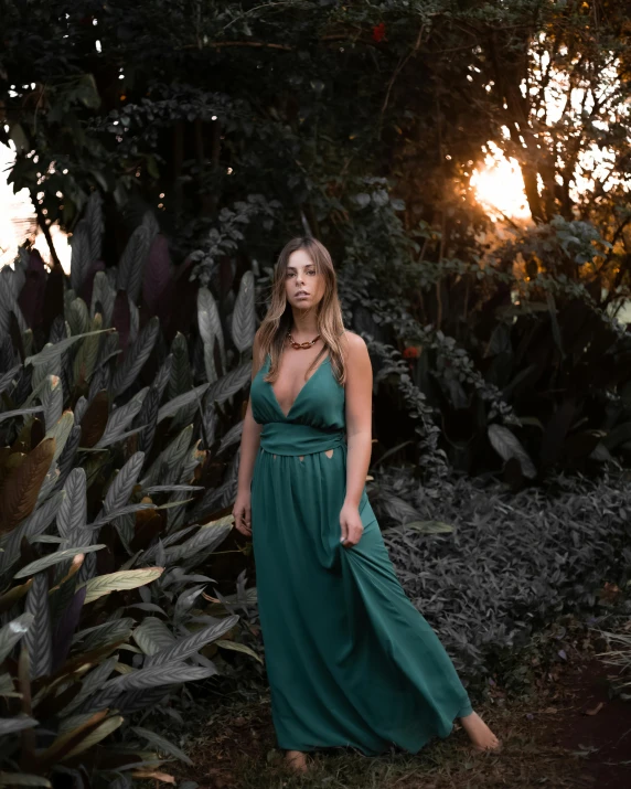a woman in a green dress standing in the grass, an album cover, inspired by Elsa Bleda, pexels contest winner, posing in waikiki, evening!! in the forest, low cut dress, ( ( ( ( kauai ) ) ) )