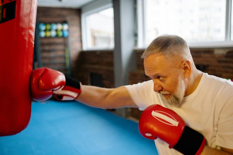 an older man in red boxing gloves hitting a punching punch