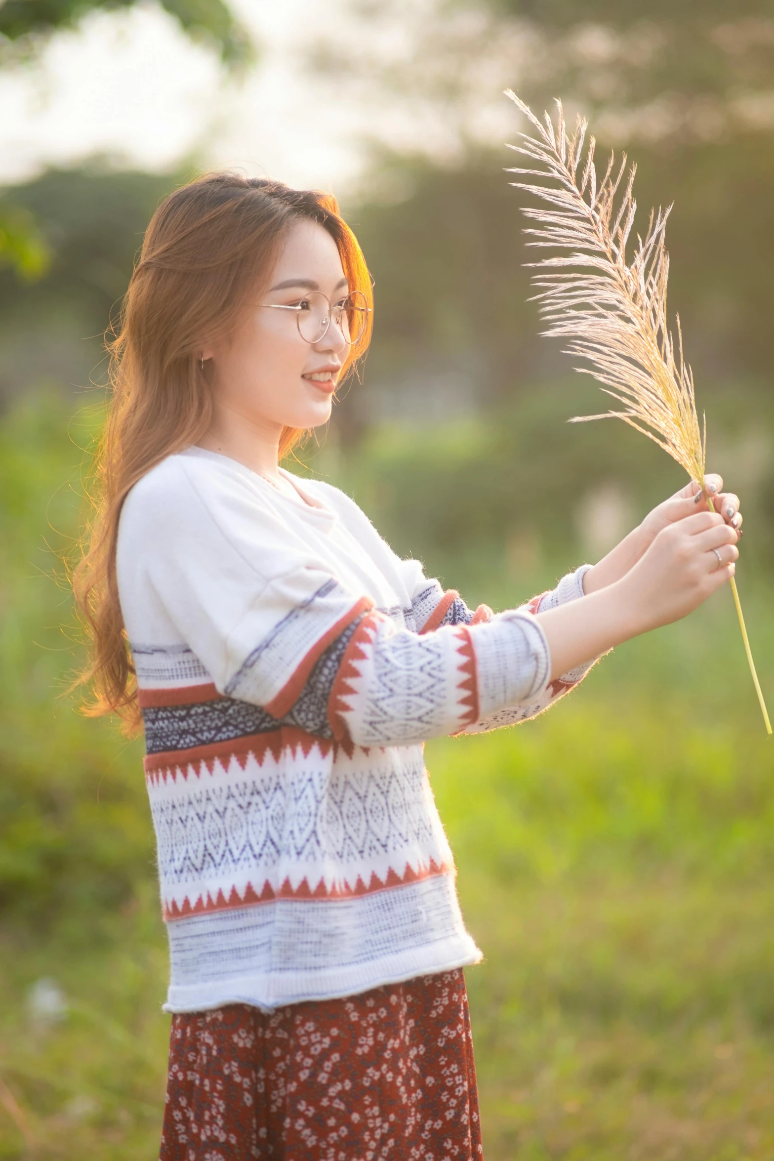 a woman standing in a field holding a plant, inspired by Kim Jeong-hui, wearing casual sweater, profile image, trending photo, traditional beauty