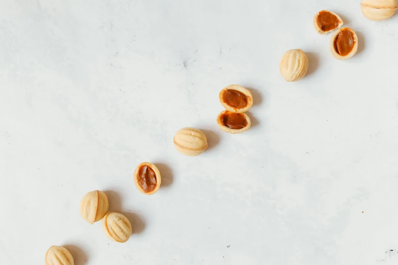 a group of nuts sitting on top of a white counter, inspired by Károly Patkó, pale orange colors, jasmine, slightly minimal, thumbnail