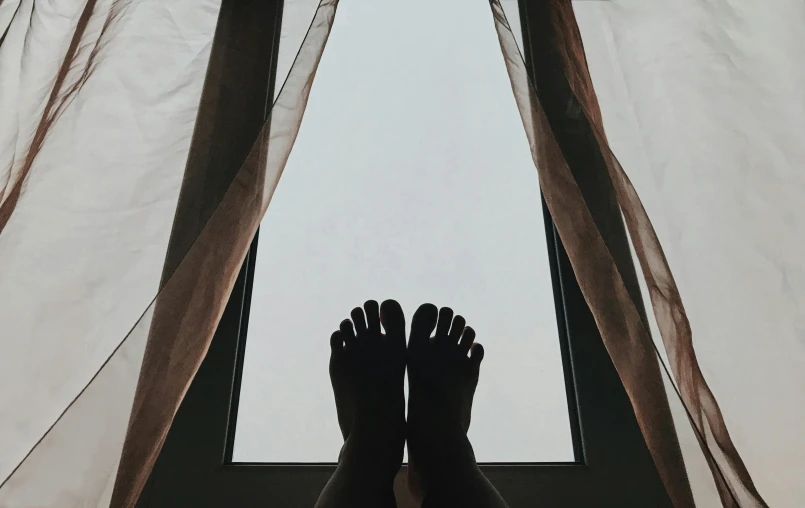 the feet of a person standing in front of a window, laying down, looking up onto the sky, cosy vibes, tans