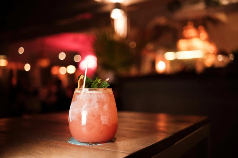 a drink sitting on top of a wooden table, by Carey Morris, unsplash, renaissance, chinatown bar, pink, tropical, saturday night in a saloon