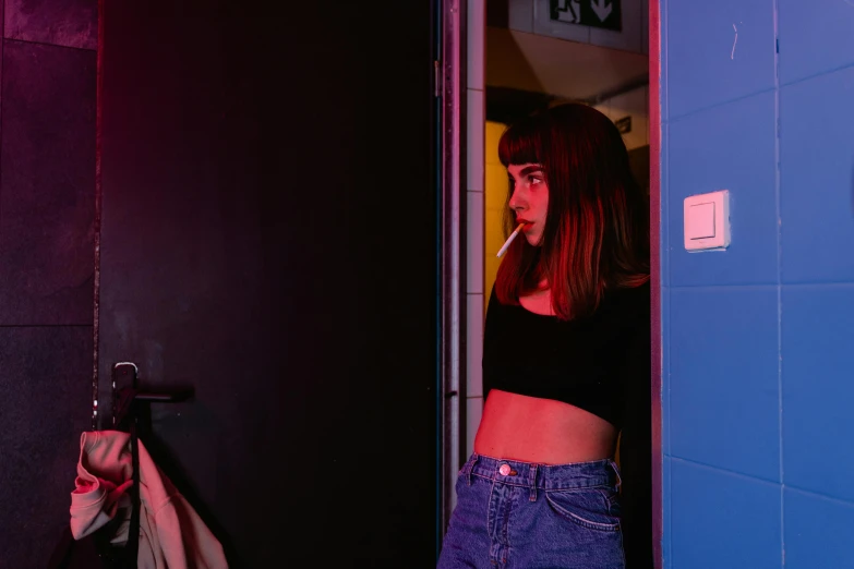 a woman standing in a doorway with a cigarette in her mouth, an album cover, inspired by Elsa Bleda, pexels contest winner, straight bangs, neon basement, calmly conversing 8k, wearing crop top