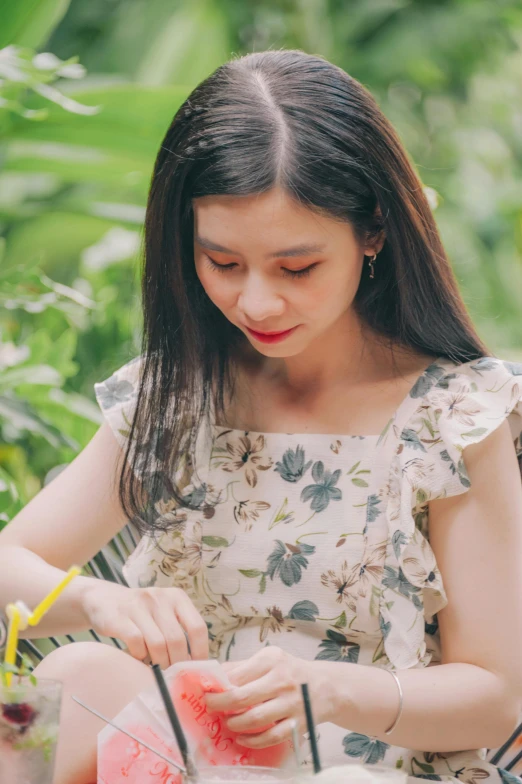 a woman sitting in a chair eating a slice of watermelon, a picture, inspired by Li Fangying, pexels contest winner, wearing yellow floral blouse, writing in journal, aesthetic cute with flutter, sundress
