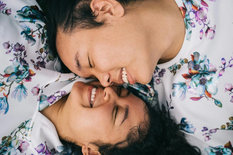 a couple laying on top of a bed next to each other, by Julia Pishtar, trending on unsplash, happening, lesbian embrace, close up face, louise zhang, smiling down from above