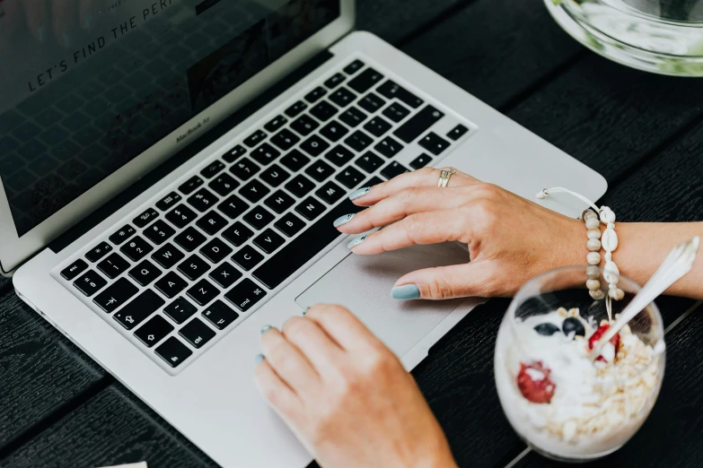 a close up of a person typing on a laptop, by Carey Morris, trending on unsplash, having a snack, wearing business casual dress, back of hand on the table, 15081959 21121991 01012000 4k