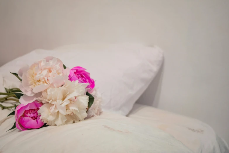 a bouquet of flowers sitting on top of a bed, inspired by Allan Ramsay, unsplash, romanticism, white and pink, resting on a pillow, shot on sony a 7, beds