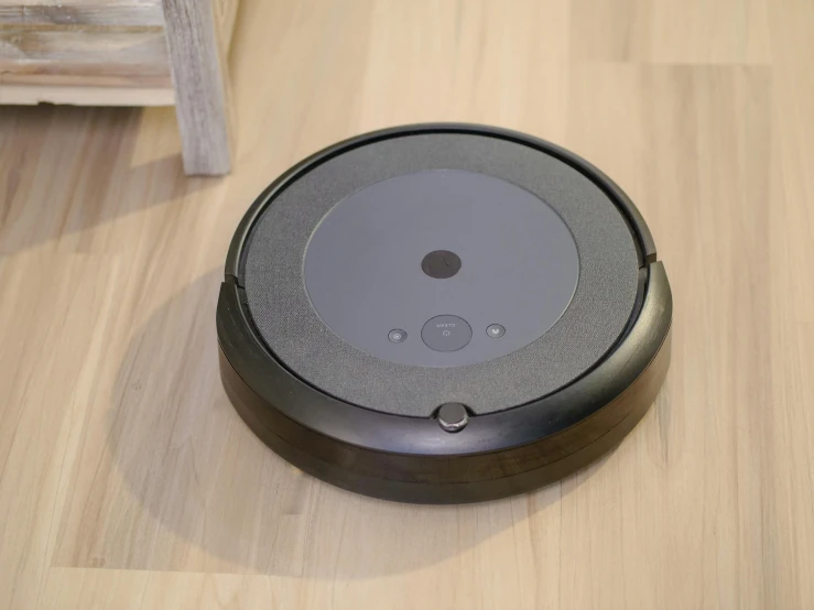 a black robot sitting on top of a wooden floor, dish, dust swirling, placed in a large living room, product image