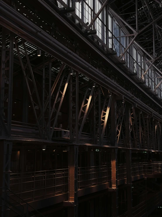 a train traveling through a train station next to a tall building, inspired by Andreas Gursky, unsplash, light and space, hyperdetailed metalwork, 8 k. volumetric lighting. dark, truss building, louvre collection