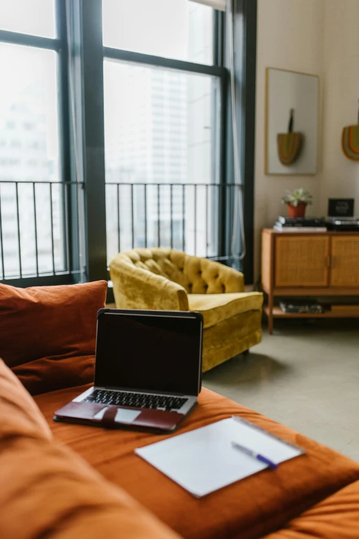 a laptop computer sitting on top of an orange couch, by Carey Morris, trending on unsplash, modernism, city apartment, open plan, brown, golden computers