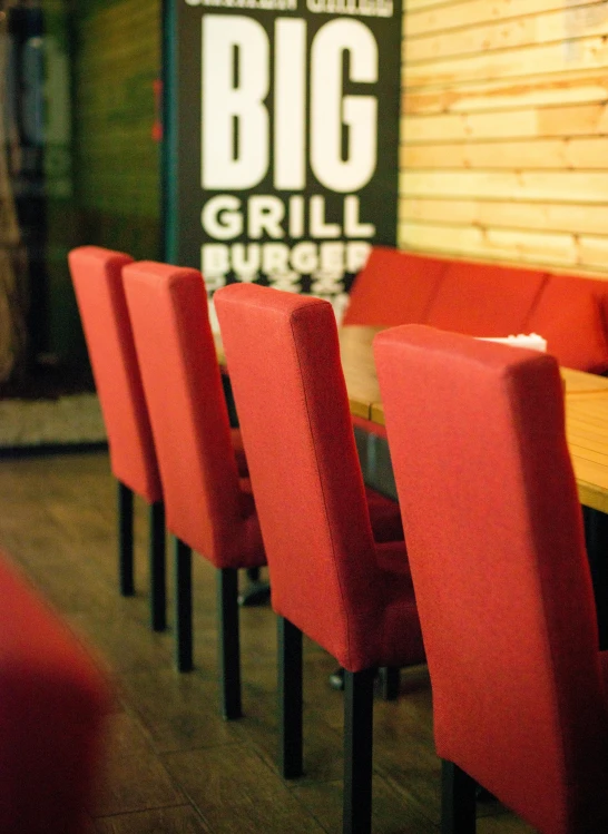 a group of red chairs sitting next to a wooden table, big juicy burger, profile image
