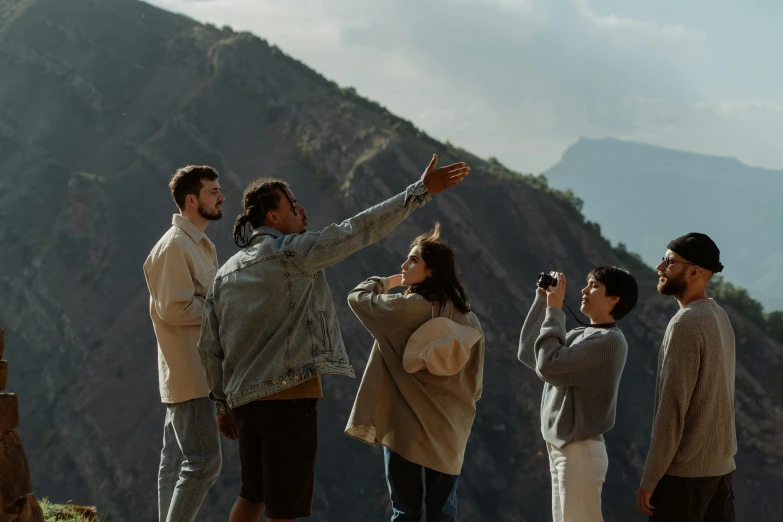 a group of people standing on top of a mountain, pexels contest winner, looking to the side off camera, shot from roofline, flying shot, behind the scenes