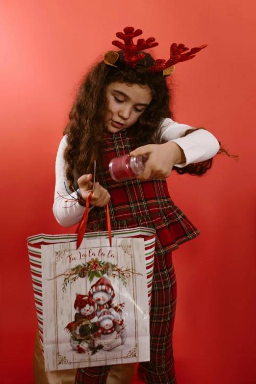 little girl dressed as santa clause with a christmas bag