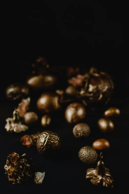 a bunch of nuts sitting on top of a table, a still life, unsplash, baroque, carbon black and antique gold, intricate alien botanicals, dragon eggs, burnt umber