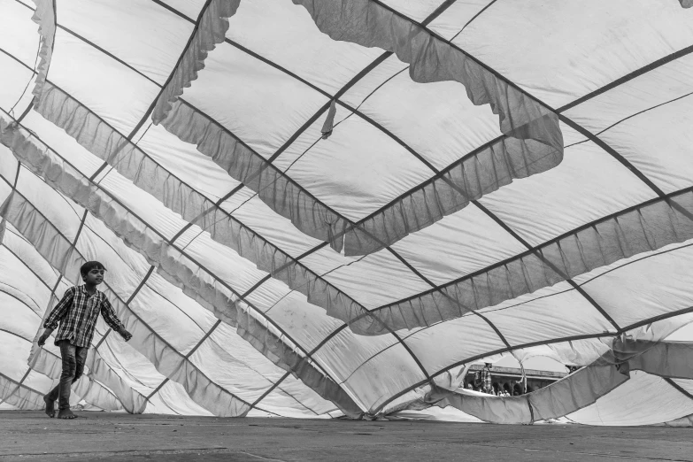 a black and white photo of a person on a skateboard, by Christo, temporary art, interior of a tent, desert white greenhouse, torn sails, under repairs