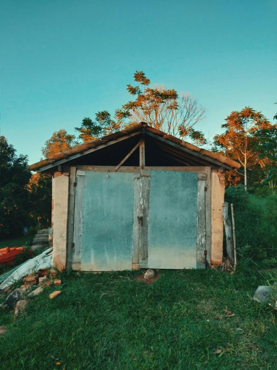 an outhouse made from a wooden shed sitting on top of green grass