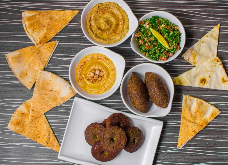 a table topped with plates of food and pita chips, dau-al-set, dan mumfor, listing image, vista view, offering a plate of food