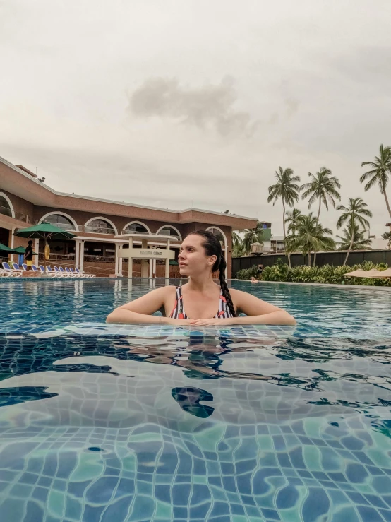 a woman swimming in a pool surrounded by palm trees