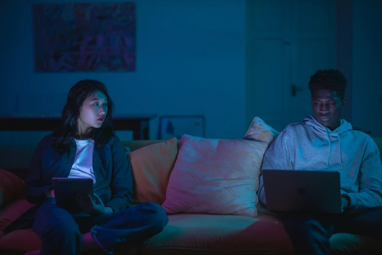 two people sitting on a couch looking at a laptop, by Carey Morris, pink and blue lighting, lee madgwick & liam wong, teenage girl, concerned