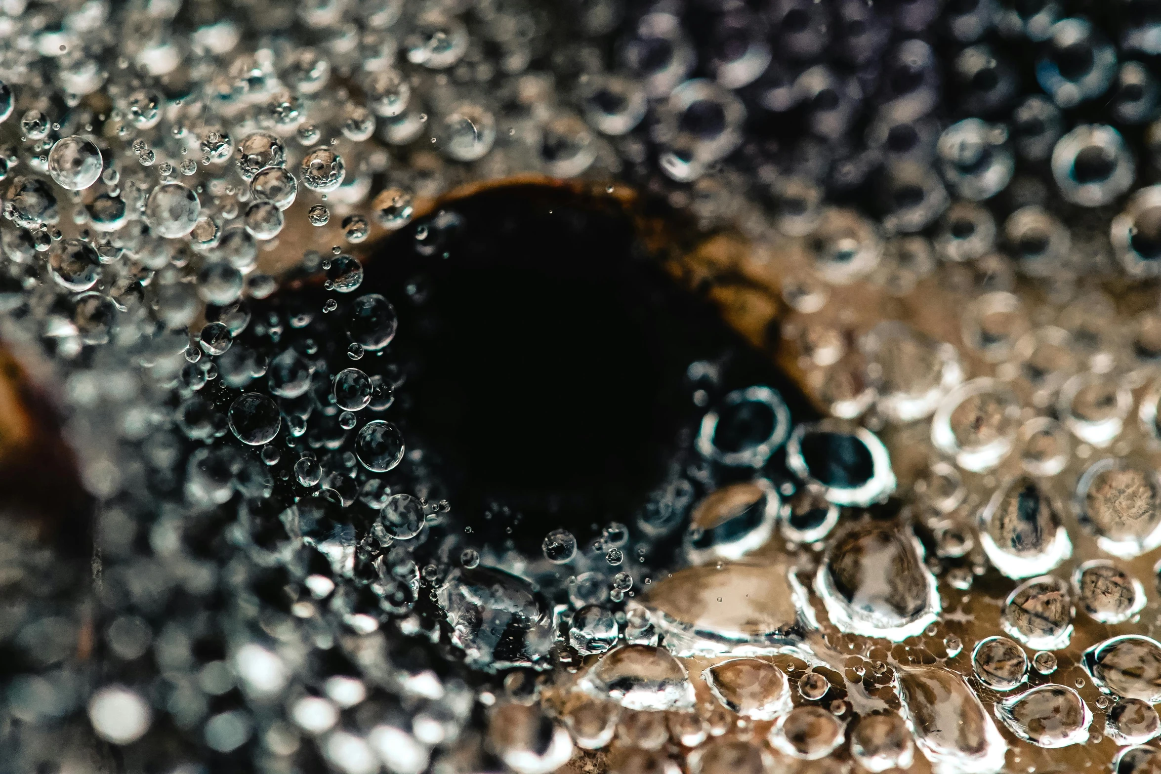 a close up of water bubbles on a piece of wood, a macro photograph, trending on unsplash, charcoal and champagne, black round hole, cold brew coffee ), black