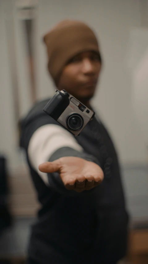 a man holding a camera in his hand, hero pose, 35mm —w 1920 —h 1080, 8k resolution. tupac, low quality photo