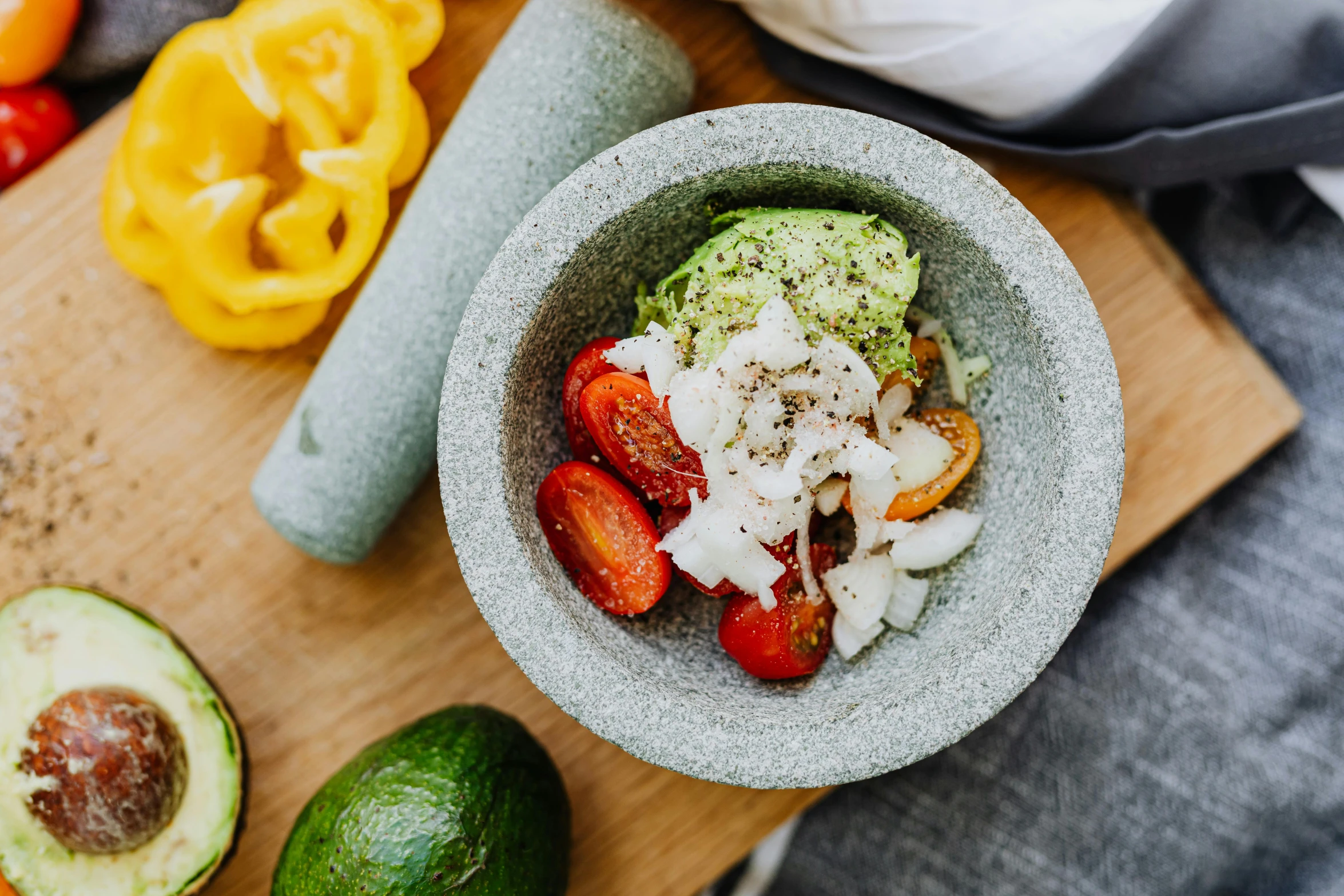 a bowl of food sitting on top of a cutting board, by Julia Pishtar, unsplash, mexican, mortar, background image, avocado