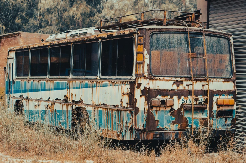 a rusty bus sitting in a field next to a building, unsplash, auto-destructive art, cyprus, fan favorite, 2000s photo, metal rust and plaster materials