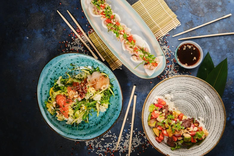 a table topped with plates of food and chopsticks, profile image, blue, thumbnail, oceanside