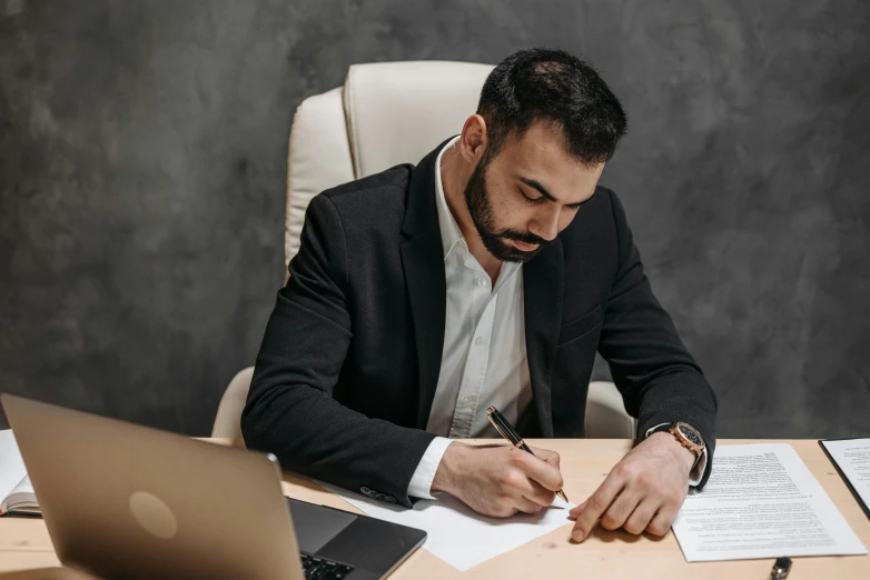 a man sitting at a desk writing on a piece of paper, pexels contest winner, man in black suit, worksafe. instagram photo, ash thorp khyzyl saleem, wearing business casual dress