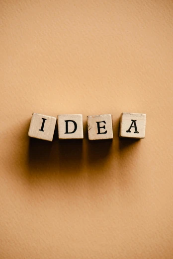 three dices spelling the word idea on a brown background