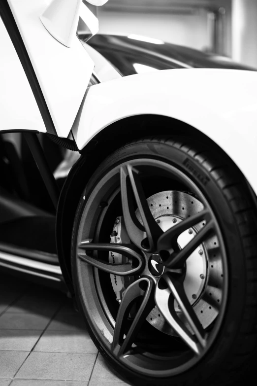 a black and white photo of a sports car, pexels contest winner, precisionism, white wheel rims, mclaren, detailed alloy wheels, uploaded