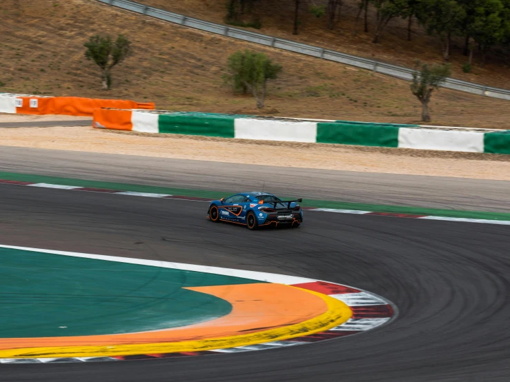 an automobile drives on the track with orange stripes