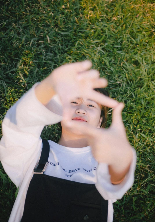 a little girl laying in the grass with her hands up to show the side