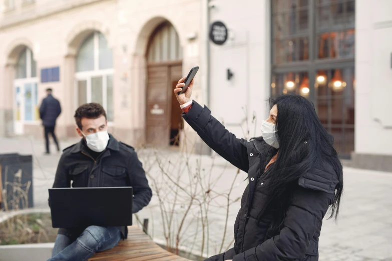 the two people sit and talk in front of the building, and one woman is holding a phone