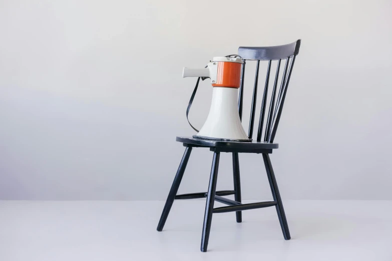 a white and orange blender sitting on top of a wooden chair, trending on unsplash, purism, raygun gothic style, black armchair, hairdryer, 1960s