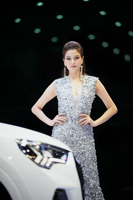 a woman in a silver dress next to a white car