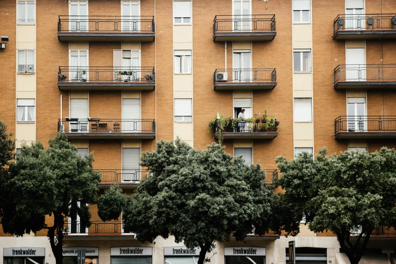 a couple of cars that are parked in front of a building, by Nicolette Macnamara, pexels contest winner, modernism, plants on balconies, ten flats, 2 5 6 x 2 5 6, massive trees with warm windows